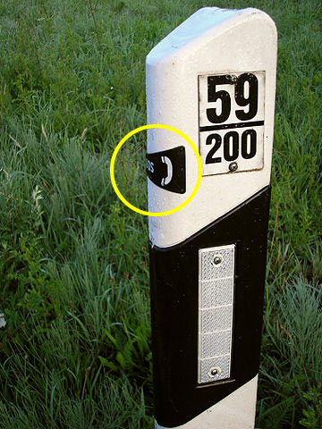 Reflecting guide post pointing towards nearest emergency telephone.
